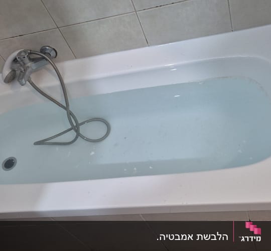 אמבטיה עם מים וברז על קיר אריחים